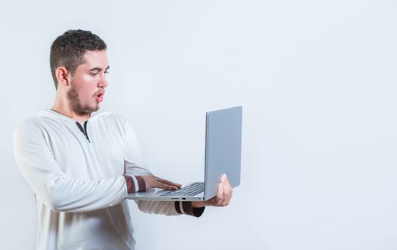 Surprised guy holding and looking at an promotion on laptop screen. Amazed handsome man standing using laptop isolated