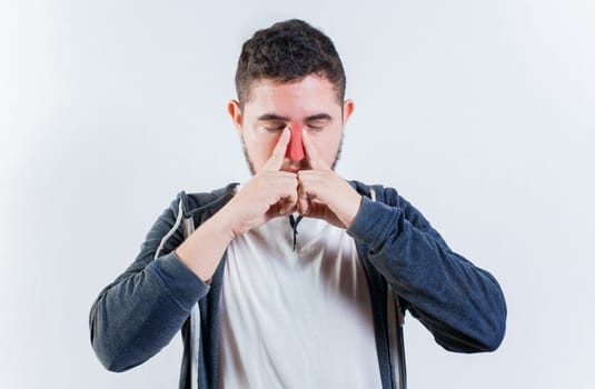 Suffering man with nasal congestion isolated. Sore person suffering with nasal bridge on isolated background