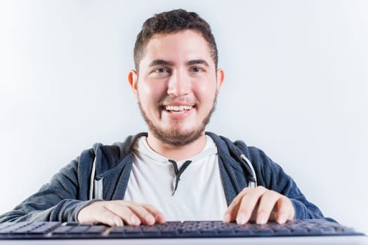 Portrait of nerdy man in front of keyboard. Smiling nerdy guy with hands on keyboard smiling at camera