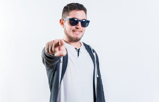 Handsome guy in sunglasses smiling and pointing at the camera isolated