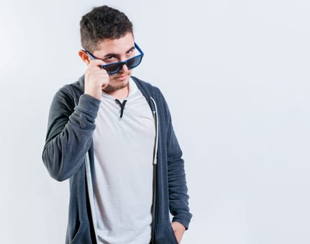 Handsome guy lowering his glasses looking at the camera. Attractive young man in glasses looking at camera isolated