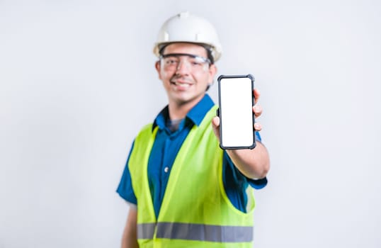 Smiling engineer showing cell phone screen isolated. Young construction engineer showing an advertisement on the phone screen