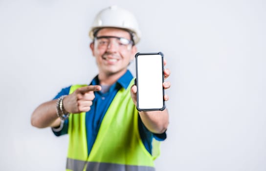 Young construction engineer showing and pointing at an advertisement on the phone screen. Happy engineer showing cell phone screen isolated