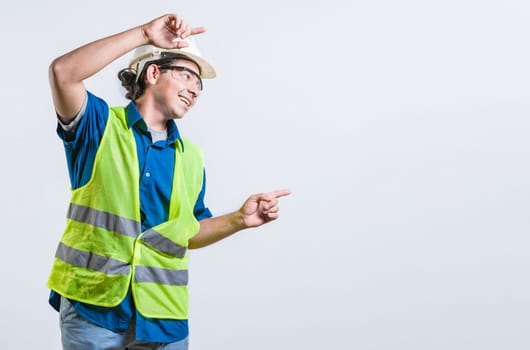 Smiling latin engineer pointing to the side with both fingers isolated. Happy male builder pointing an advertisement isolated