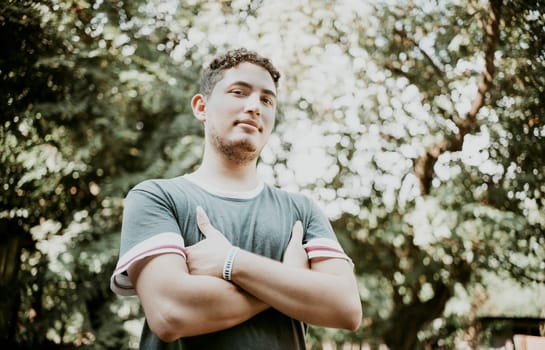 Latin American man with crossed arms smiling at camera. Portrait of handsome latin guy outdoors