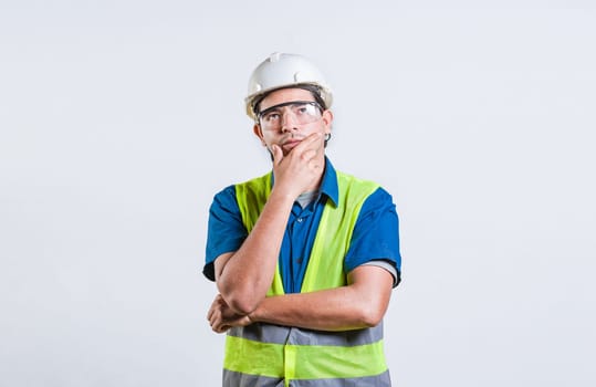 Young builder wondering looking up with hand on chin. Pensive builder man with hand on chin isolated