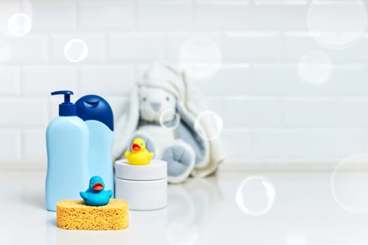 Yellow rubber duck, soap, bath foam on bath background, children bath accessories. copy space