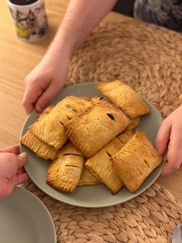 Close-up man at a kitchen table with a plate of freshly baked pastries top view. Cozy, inviting atmosphere to the scene of homemade delight