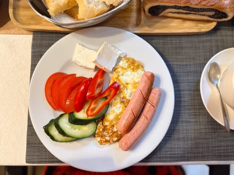 vibrant breakfast plate features sausages, fried eggs, fresh vegetables, and cheese, ready to be savored. the setup includes a backdrop of bread and coffee, capturing a perfect morning meal scene