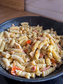 Delicious bowl of creamy rotini pasta mixed with pieces of chicken and vibrant vegetables is served fresh and ready to eat. Dish showcases a perfect blend of flavors and textures, making it an appetizing choice for any meal.