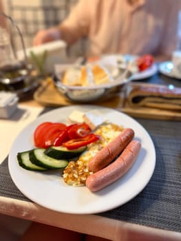vibrant breakfast plate features sausages, fried eggs, fresh vegetables, and cheese, ready to be savored. the setup includes a backdrop of bread and coffee, capturing a perfect morning meal scene