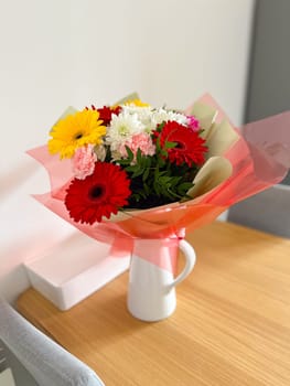 Vibrant bouquet of colorful flowers arranged in a white vase brightens up the room. the mixture of red, yellow, and pink blooms creates a cheerful and lively atmosphere, perfect for any celebration