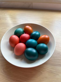 Bowl of vibrant colored Easter eggs standing on a wooden surface, beautifully festive and joyful atmosphere. Easter and religious holidays.
