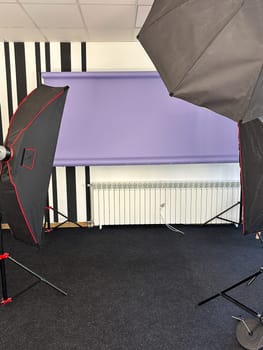 Professional photography studio setup with lighting equipment and a purple backdrop. the studio is well-equipped and ready for a photo session or video recording.