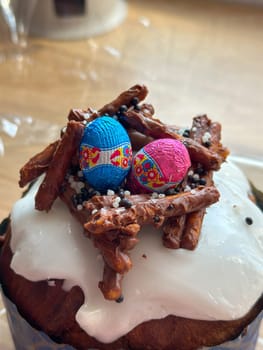 Festive easter cake is decorated with colorful chocolate eggs and crunchy pretzel sticks, creating a nest on top. Christian spring celebrations.