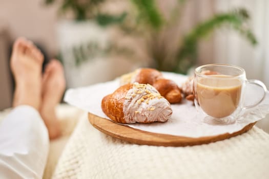 fresh french croissants and glass of coffee on wooden tray for breakfast in bed in the morning, tasty breakfast