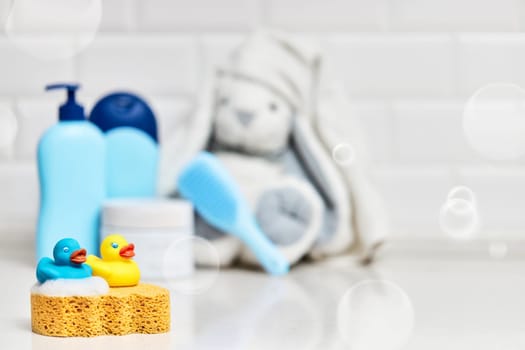 Yellow rubber duck, soap, bath foam on bath background, children bath accessories