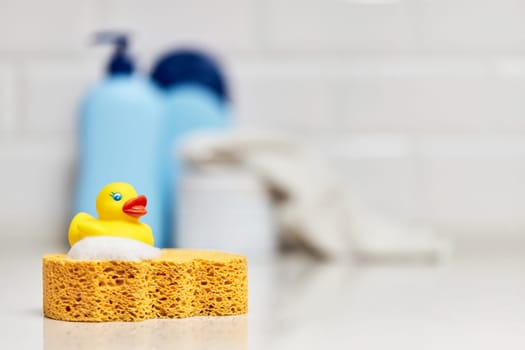 Yellow rubber duck, soap, bath foam on bath background, baby bath accessories