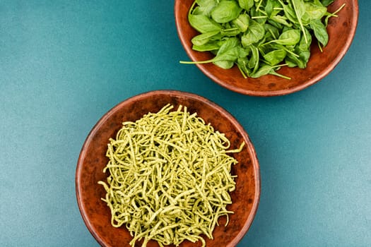 Spaghetti pasta with spinach and green on wooden table. Raw Italian food