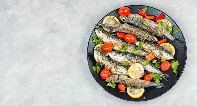 Oven baked Italian fish sardoncini or sardines, with tomatoes, lemon and rosemary on a rustic baking tray.