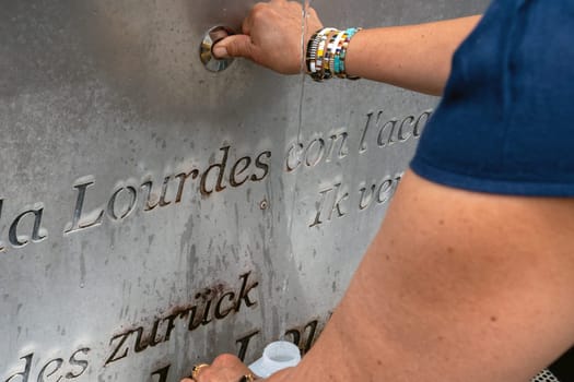 A woman is pouring water from a fountain, Lourdes, France