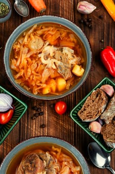 Tasty soup with meat on rustic wooden table. Traditional Ukrainian borscht. Top view.