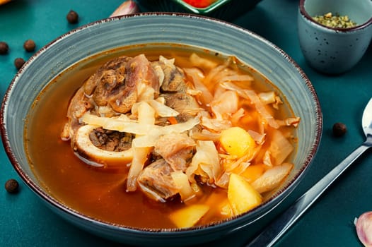 Tasty soup with meat on rustic wooden table. Traditional Ukrainian borscht. Top view.