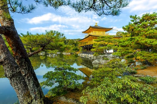 The kinkaku-ji golden pavilion kyoto reflecting  lake surrounded by trees