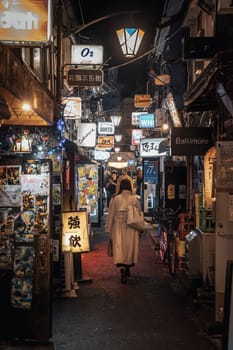 Woman walking through alley in shinjuku at night