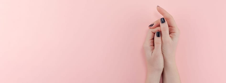 Stylish trendy female black manicure. Beautiful young woman's hands on millennial pink pastel background. Beauty and SPA concept. Banner Template for feminine blog social media