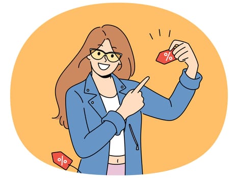 Happy woman announces discounts for shopping and buying clothes, pointing finger at tag with percentage symbol. Girl promoter invites to sale in mall and promises big discounts on black friday