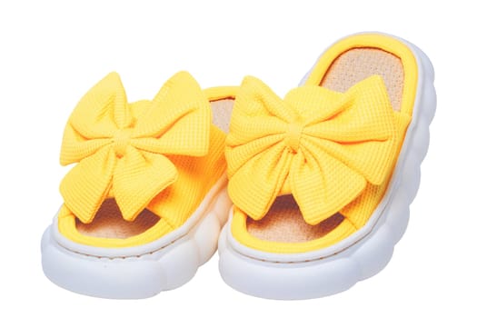 Slippers isolated. Close-up of a pair female yellow soft cosy house slipper with a large bow isolated on a white background, Clipping path. Macro. Womans shoes.