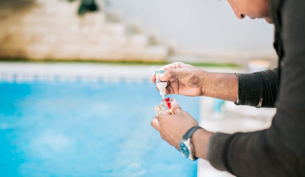 Man using tester kit to measure chlorine and ph in swimming pools. Person testing the PH of the swimming pool
