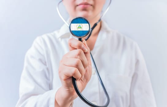 Female doctor holding stethoscope with Nicaragua flag. Nicaraguan Health and Care concept
