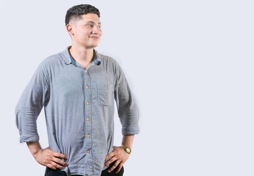 Satisfied young man with hands on hip looking to side. Young man with hands on hips looking at an advertisement to the side
