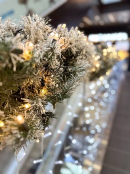 Close-up shot captures a beautifully frosted garland adorned with twinkling lights in Christmas festive indoor setting. Warm glow creates a magical atmosphere, perfect for the holiday season.
