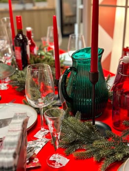 Christmas set table is adorned with festive decorations, ready for a joyful winter holiday gathering. Vibrant red tablecloth and elegant tableware create a warm and inviting atmosphere.