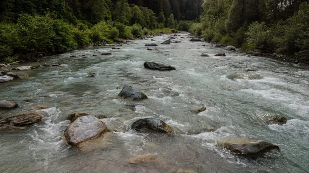 Mountain river in a splendid alpine setting. Strong currents of a freezing stream running through a mountain valley.