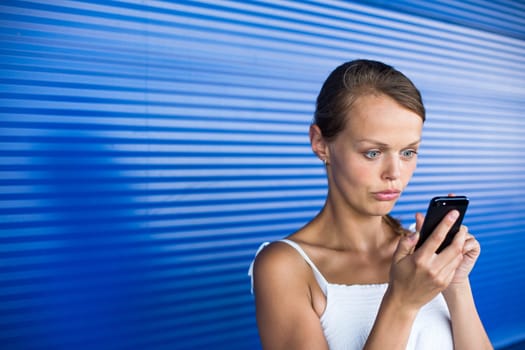 Portrait of serious businesswoman using mobile phone against blue abstract background