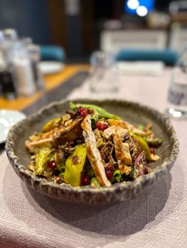 Vibrant salad is artfully presented in a rustic bowl, featuring grilled chicken, fresh greens, avocado slices, pomegranate seeds, and crunchy nuts. Appetizing dish highlights a colorful and healthy dining option perfect for any gourmet experience top view.
