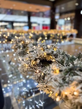 Close-up shot captures a beautifully frosted garland adorned with twinkling lights in Christmas festive indoor setting. Warm glow creates a magical atmosphere, perfect for the holiday season.