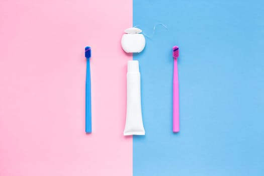 Teeth hygiene and oral dental care products on color pink and blue background with copy space. Blank tube of toothpaste and brushes. Flat lay, top view composition, mockup. Morning concept