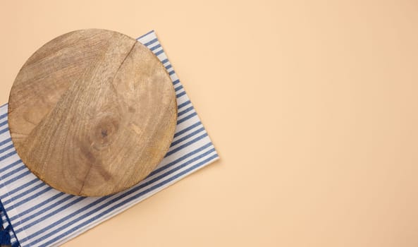 Empty round brown wooden cutting board on a brown background, top view. Copy space