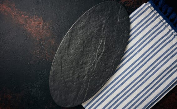 Oval stone kitchen board on black background, top view. Copy space