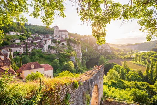 Old cliffside village of Saint-Cirq-Lapopie, one of the most beautiful villages of France,  pleasantly framed by nature at the sunset in the Lot department, Occitanie region of South West France