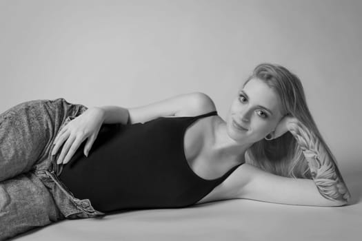 Black and white  studio shot of comfortable pregnant young woman. Horizontally.