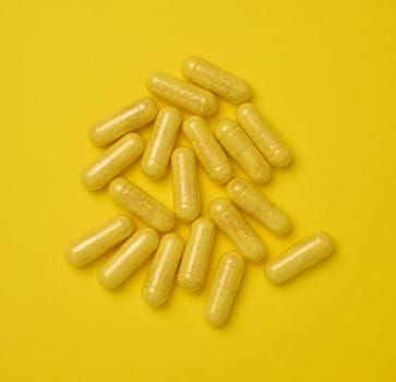Yellow pills in a capsule on a yellow background, pain treatment