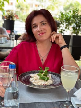 Woman enjoying a refreshing drink at an outdoor cafe in a vibrant setting. Relaxation and the joy of savoring a leisurely afternoon.