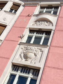 Ornate details of a historic building facade illuminated by sunlight. the intricate architectural elements and pastel colors highlight the building's elegance and charm.