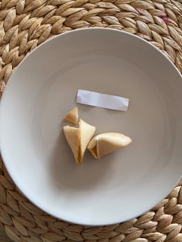 Broken fortune cookie with a blank paper slip on a gray background. Moment of anticipation and mystery that accompanies the opening of a fortune cookie.
